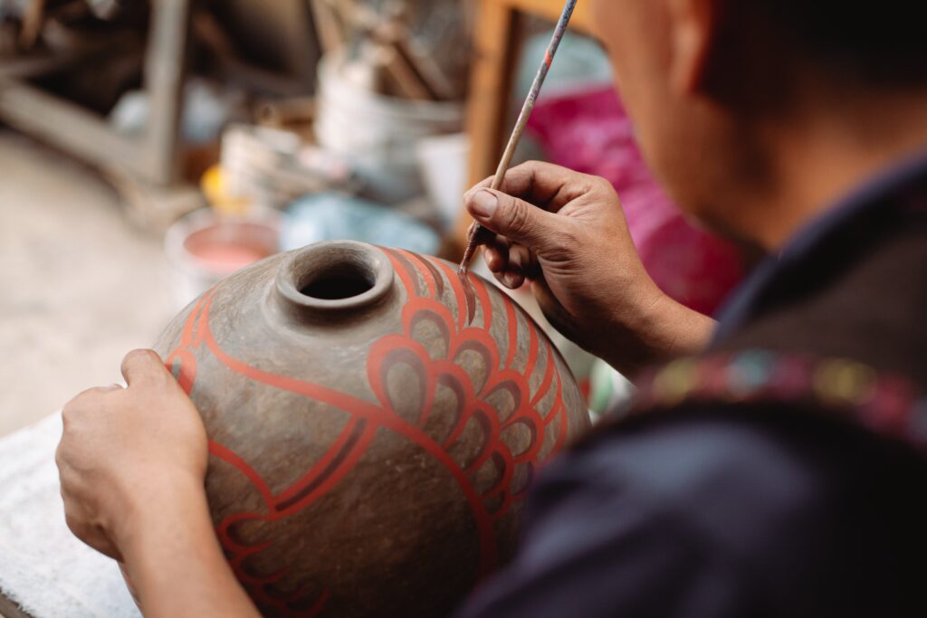 person painting on ceramic jar