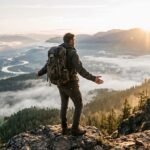 Solo traveler standing on a mountain overlook at sunrise, embracing the freedom of independent travel